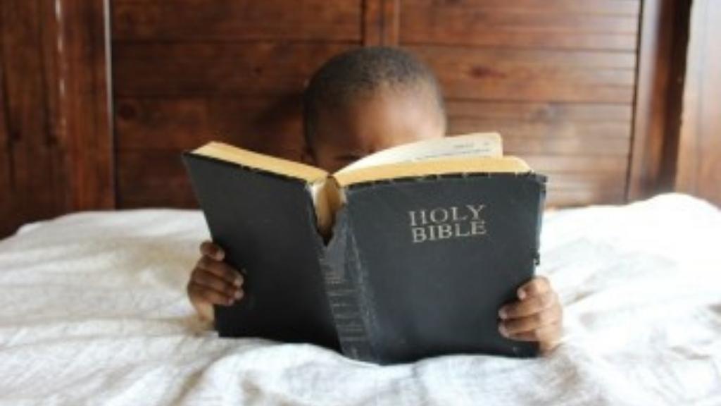 boy in bed reading Bible